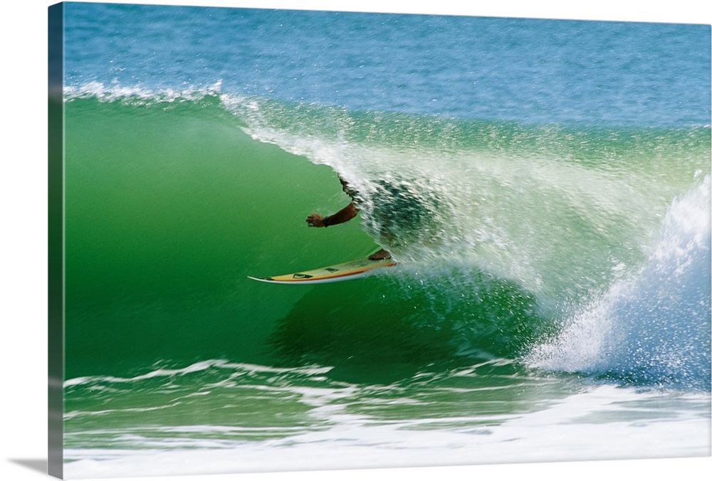 From the National Geographic Collection a landscape photograph of a surfer passing through a barrel wave.