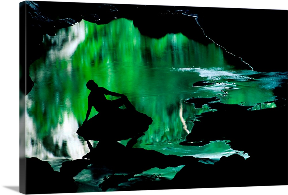 A man silhouetted against an emerald green pool of water.