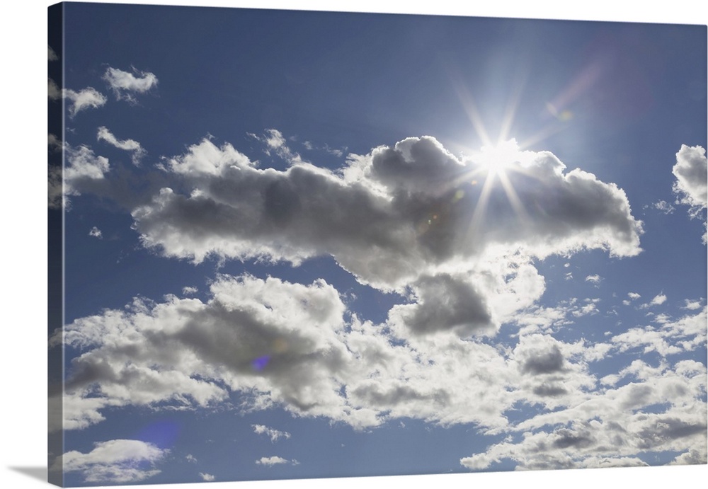Cumulus clouds in a blue sky with sunlight bursting from behind, Edmonton, Alberta, Canada.