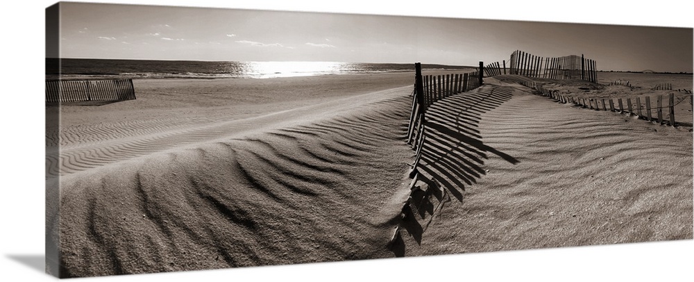 A panoramic landscape of sand dunes on a beach in sepia tones.