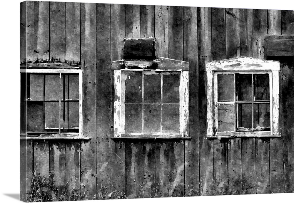 Black and white photograph of three white framed window on an aging barn.
