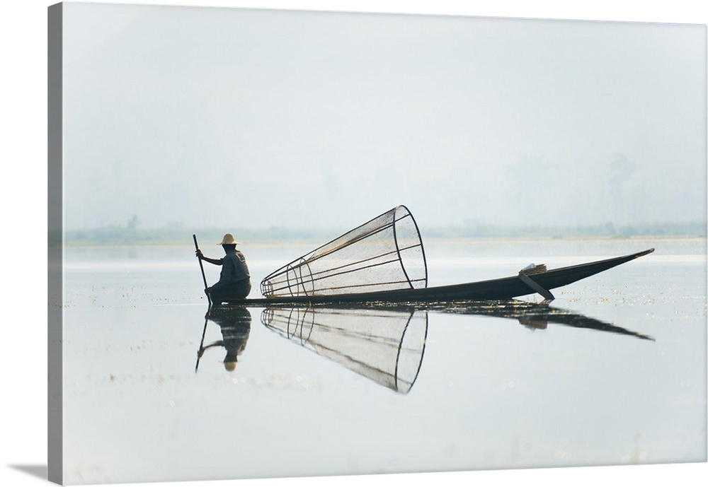 A basket fisherman on Inle Lake scans the still and shallow water for signs of life, Myanmar