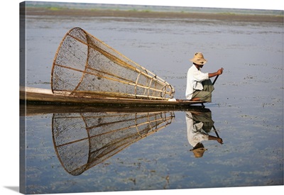 A basket fisherman on Inle Lake scans the still water for signs of life, Myanmar