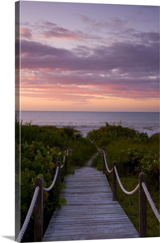 A boardwalk over sand dunes and tropical vegetation leading to the beach at sunrise, Sanibel Island, Florida, United State...