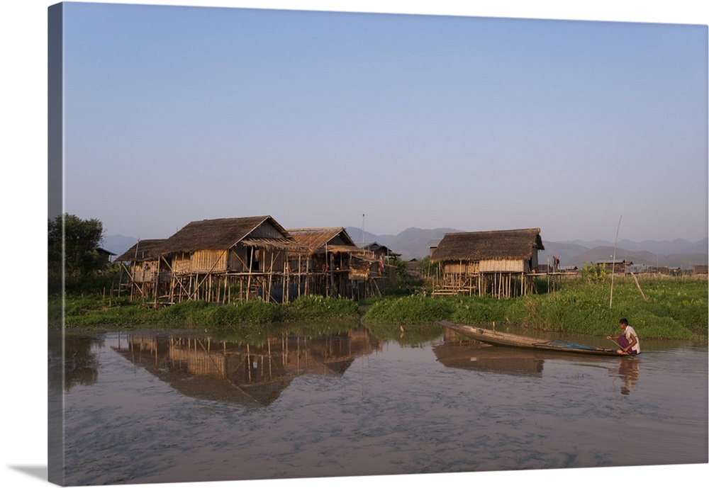 A man paddles his canoe past one of the floating villages on Inle Lake, Myanmar