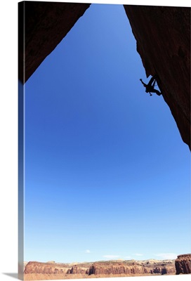 A rock climber tackles an overhanging wall on the cliffs of Indian Creek, Utah