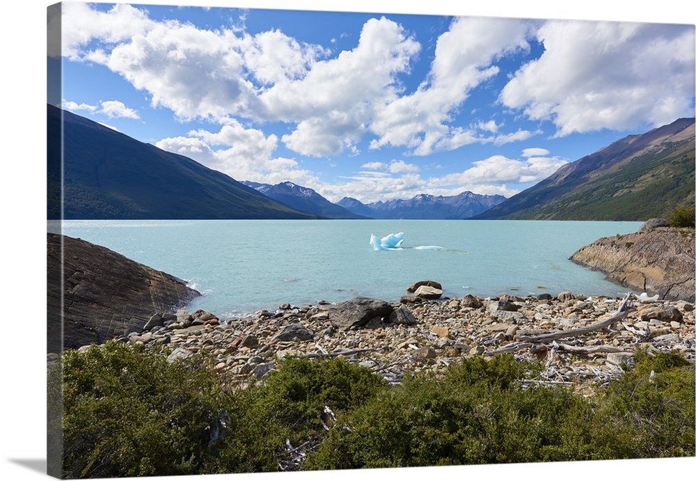 A single iceberg floating near the shore in Lago Argentino near Perito Moreno Glacier, with mountains in the background, L...