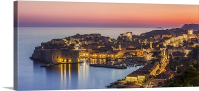 Aerial panorama of Dubrovnik Old Town at night with orange sunset sky, Croatia