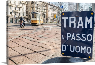 An old sign in Italian that says Trams go to Duomo, with a traditional Milanese tram