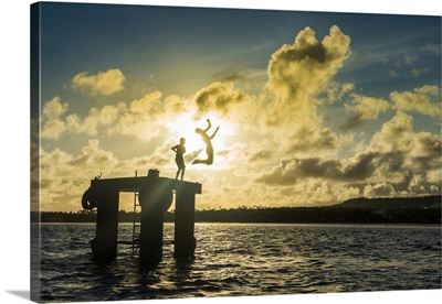 Backlit boys jumping into the water of the lagoon of Wallis from a platform