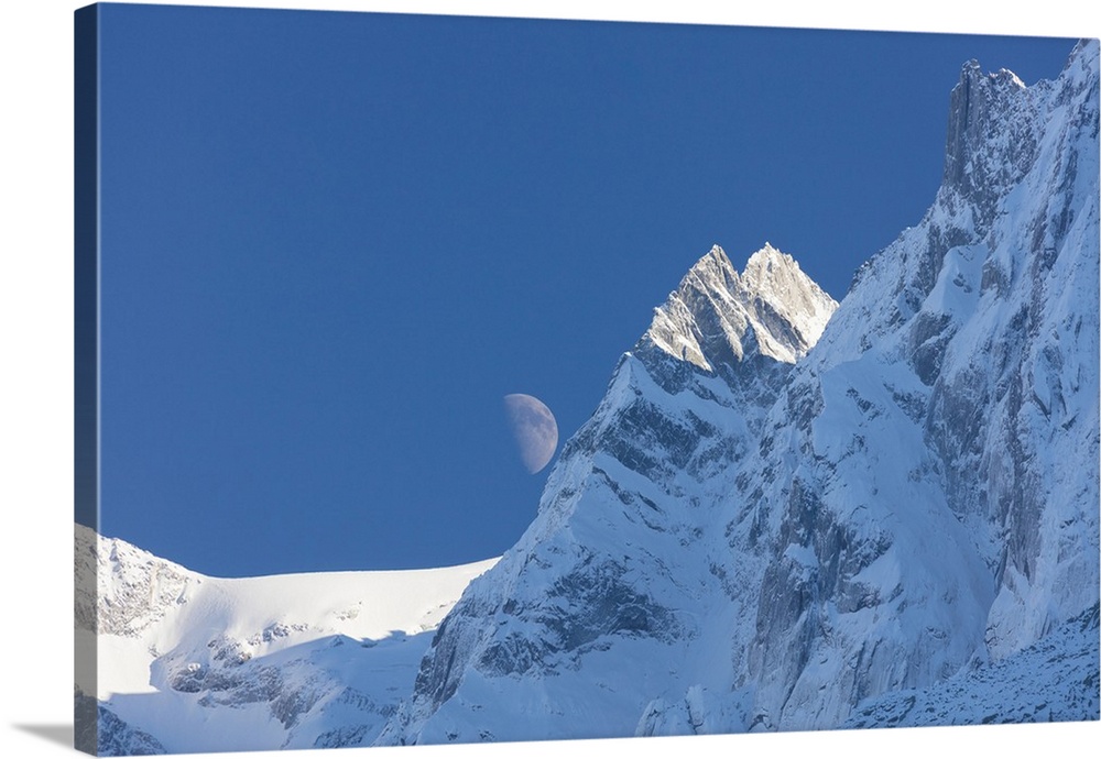 Blue sky and moon on the snowy ridges of the high peaks, Soglio, Bregaglia Valley, Canton of Graubunden, Switzerland