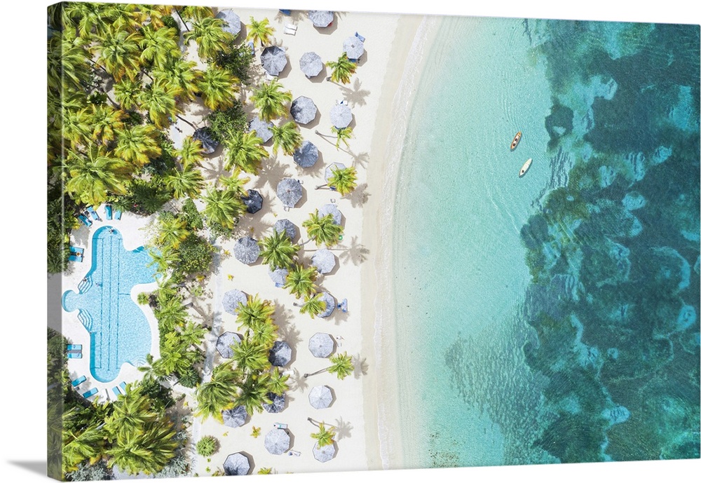 Canoes floating in the crystal sea overlooking a tropical sand beach with swimming pool, Antigua, West Indies, Caribbean, ...