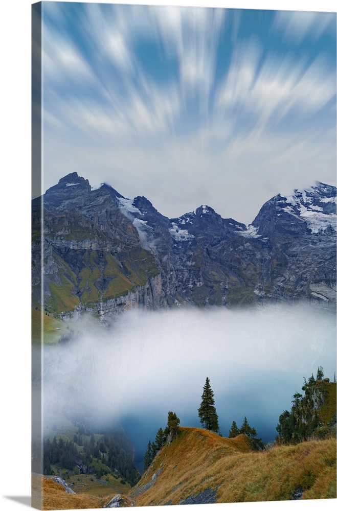 Clouds in the sky above lake Oeschinensee covered by fog, Bernese Oberland, Kandersteg, canton of Bern, Switzerland, Europe