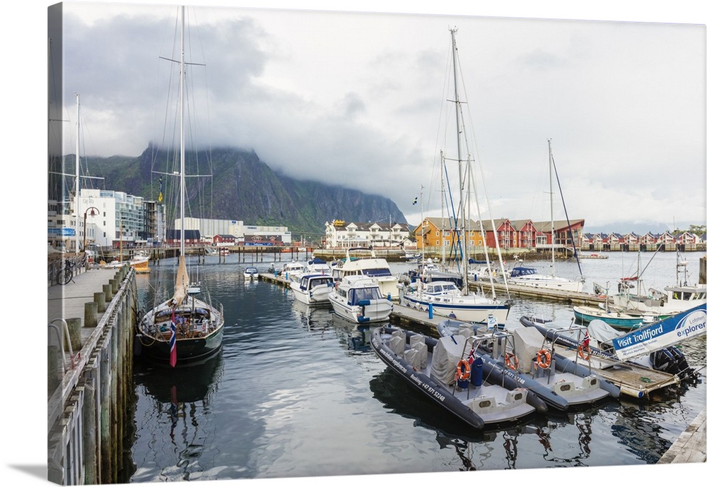 Clouds on rocky peaks frame the boats in the harbor of the fishing village of Svolvaer, Vagan, Lofoten Islands, Norway, Sc...