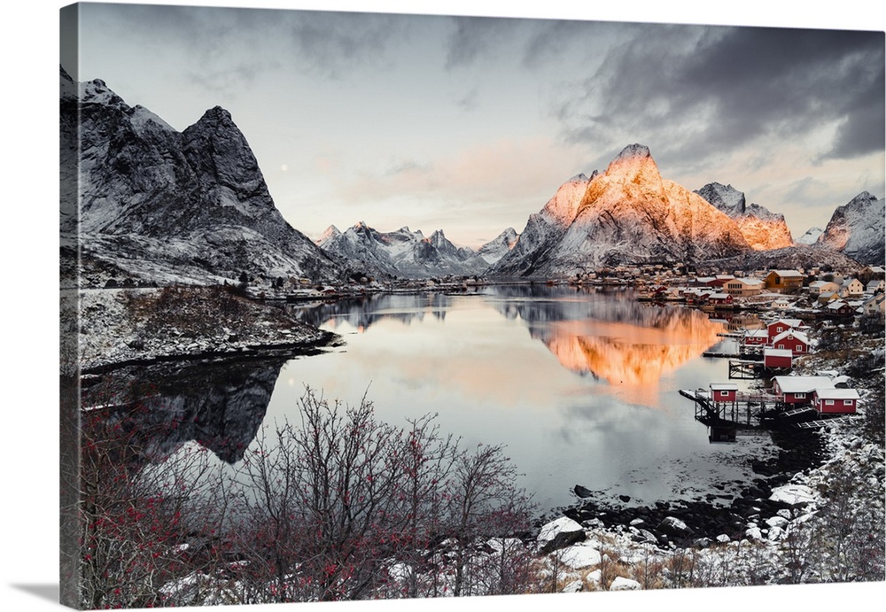 Clouds at dawn over traditional Rorbu and Olstind mountain reflected in sea, Reine Bay, Nordland, Lofoten Islands, Norway,...