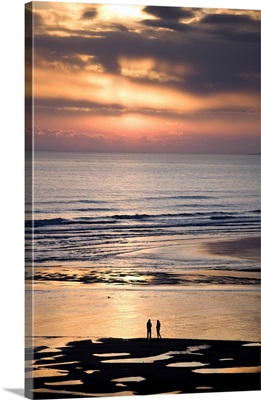 Couple in silhouette looking at North Sea at sunsrise, Northumberland, England