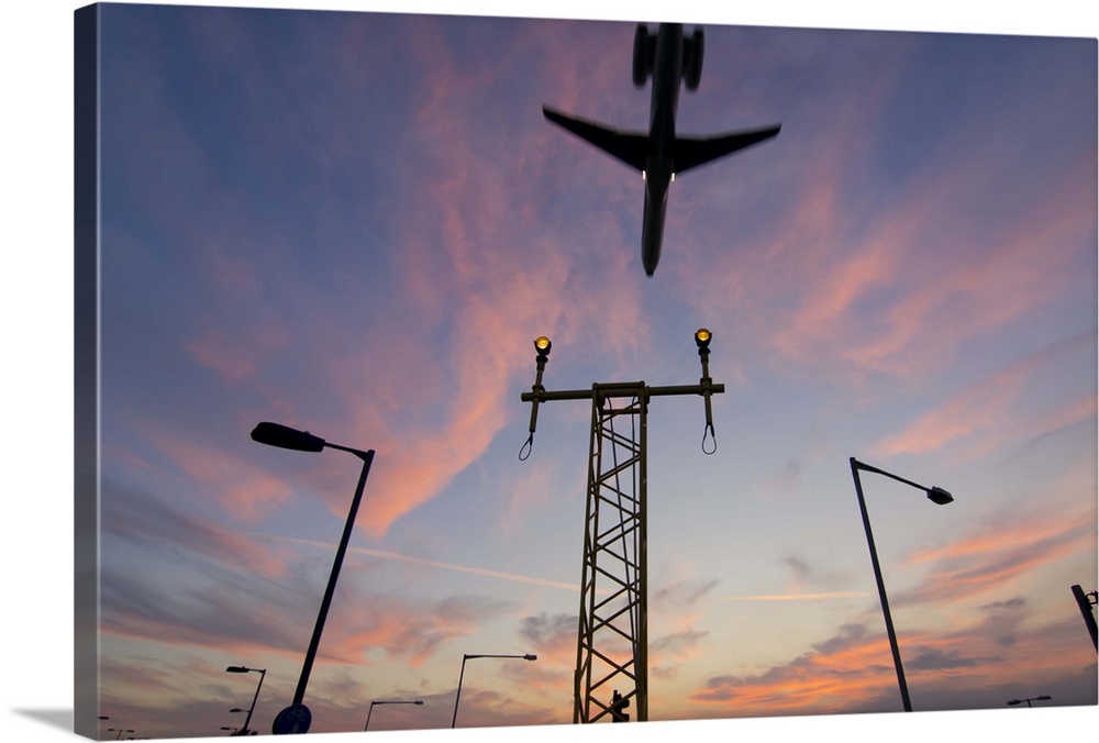 DC9 aircraft approaching over runway landing light gantries at sunset, London, England