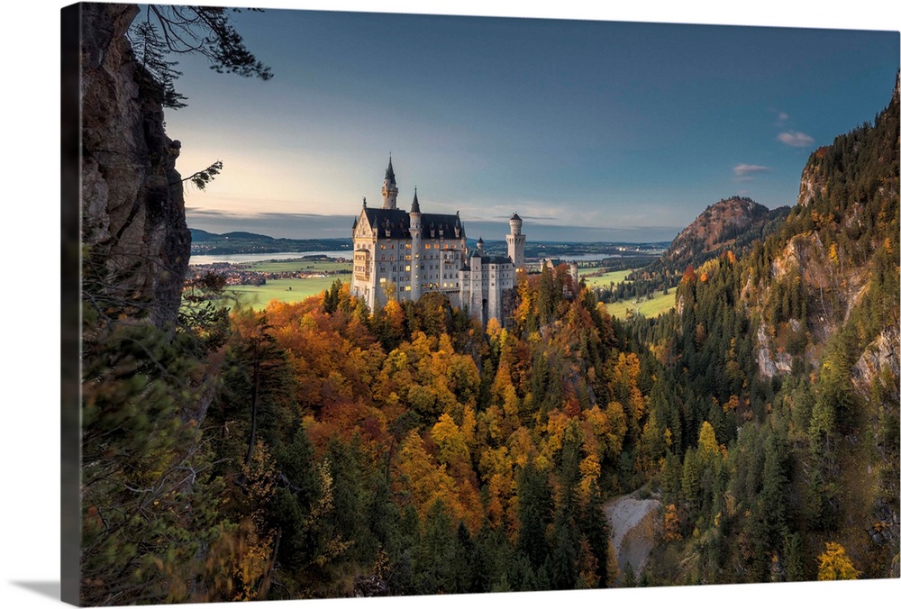 Dusk lights on Neuschwanstein Castle surrounded by colorful woods in autumn, Fussen, Bavaria, Germany