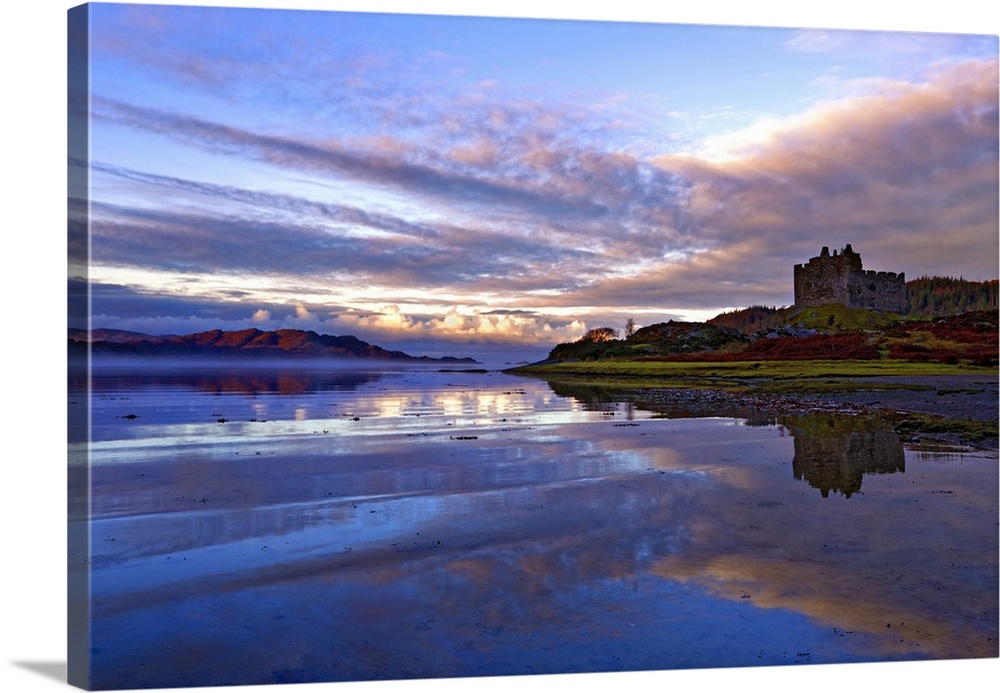 Early morning view of Castle Tioram and Loch Moidart as dawn breaks in a warm colorful sky to form attractive reflections,...