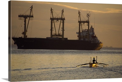 Figure silhouetted at dusk in an outrigger canoe, Manila Bay, Philippines