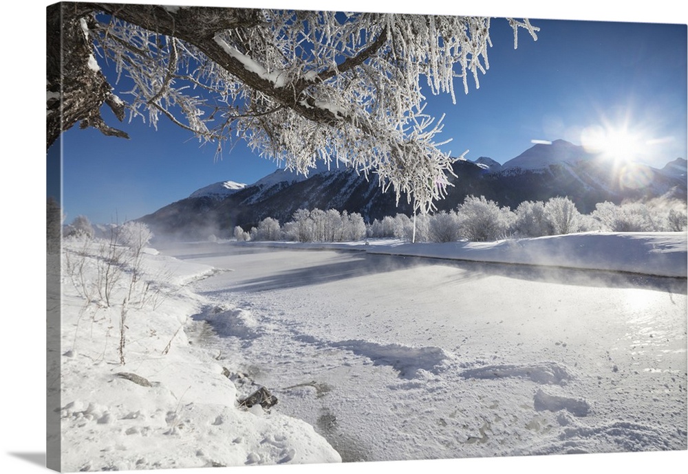 Frost on trees frame the snowy landscape and frozen river, Inn, Celerina, Maloja, Canton of Graubunden, Engadine, Switzerl...