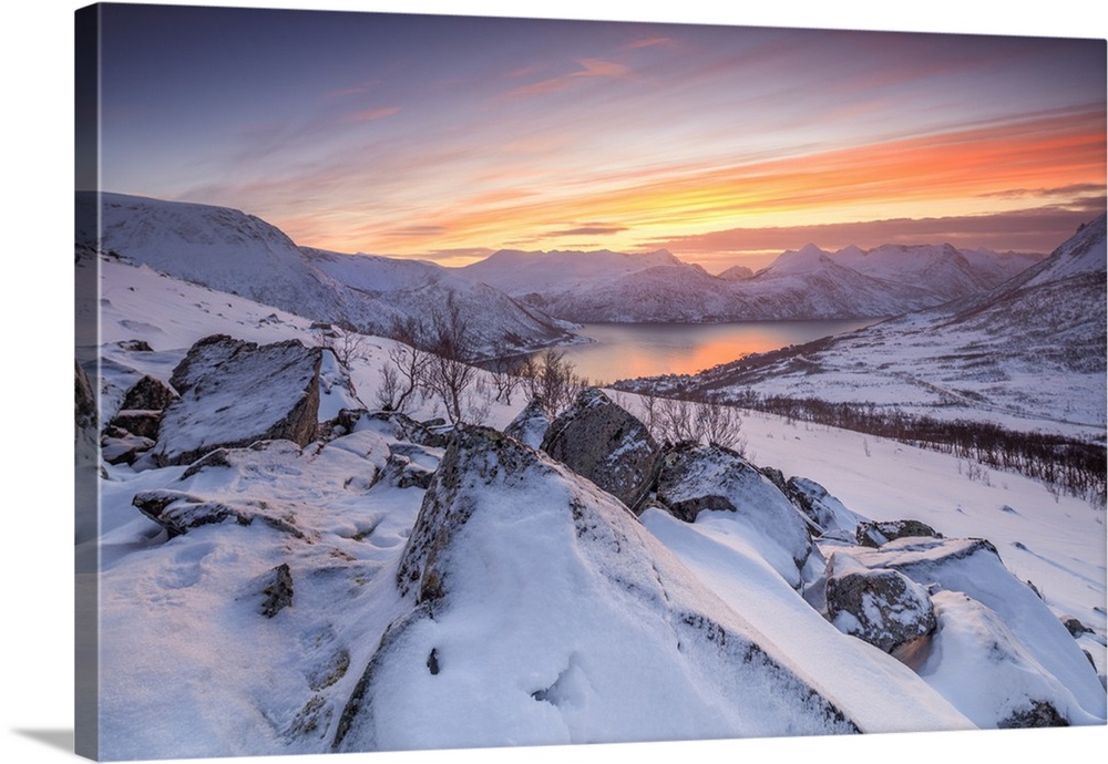 Frozen sea surrounded by snow framed by the orange sky at sunset, Torsken, Senja, Troms County, Arctic, Norway, Scandinavi...