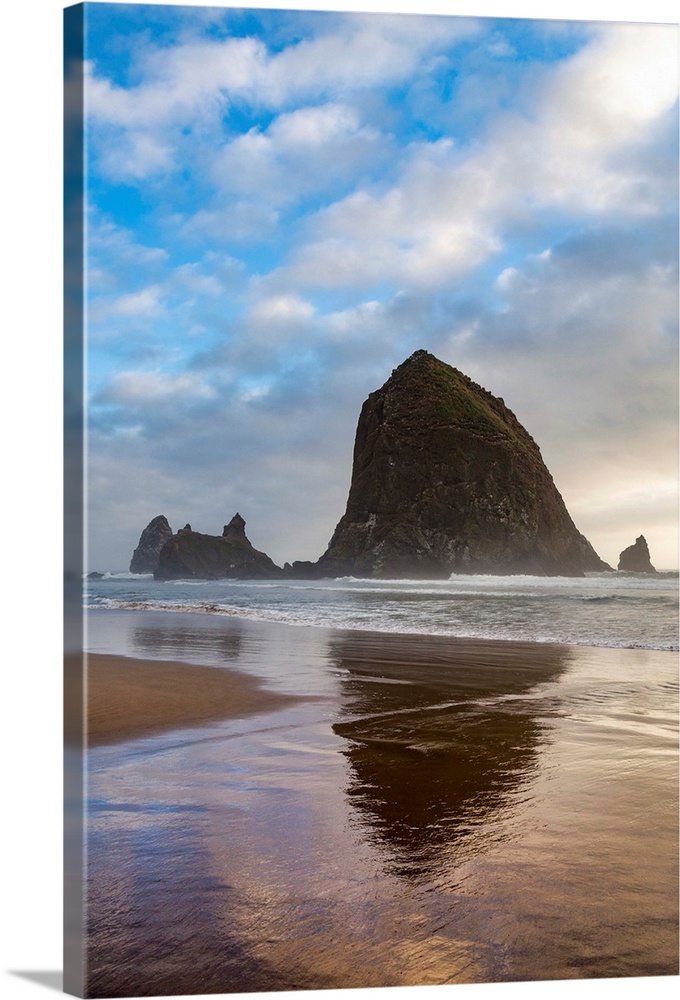 Haystack Rock reflected on the shoreline at Cannon Beach on the Pacific Northwest coast, Oregon