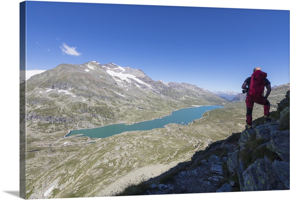 Hiker admires the blue alpine lake from Pizzo Campaccio, Bernina Pass, Canton of Graubunden, Engadine, Swiss Alps, Switzer...
