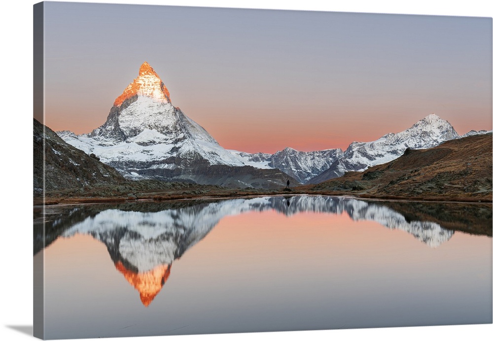 Hiker admiring the Matterhorn reflected in the Riffelsee lake at sunrise, Gornergrat, Zermatt, canton of Valais, Switzerla...