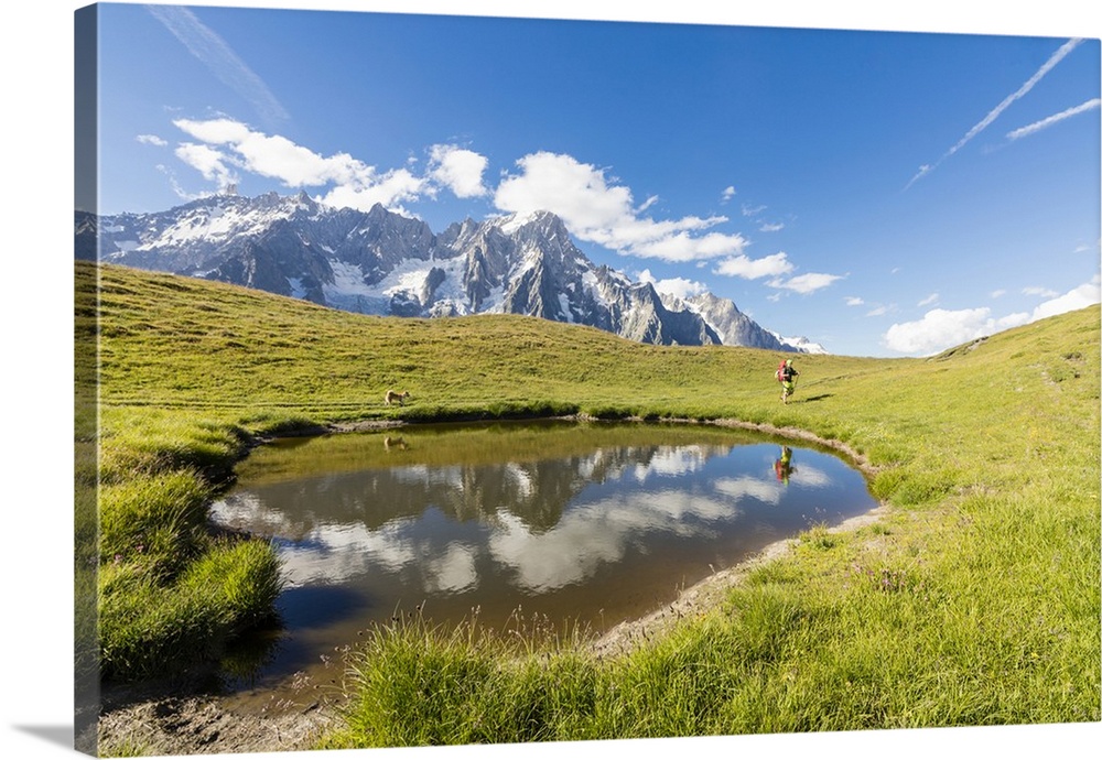 Hiker with dog admires the peaks of Mont De La Saxe reflected in water, Courmayeur, Aosta Valley, Italy