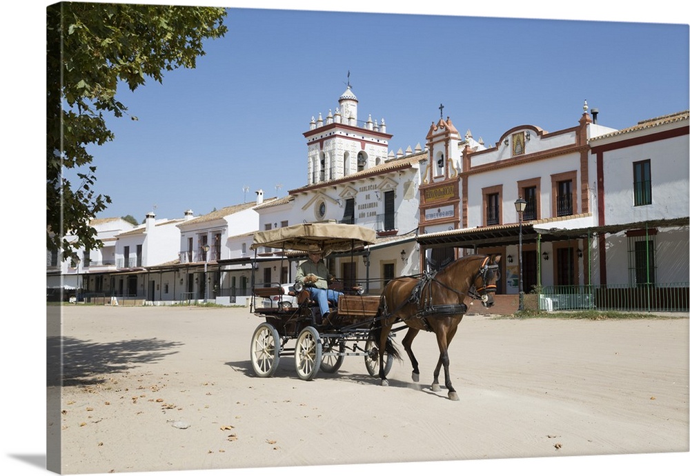 Horse and carriage riding along sand streets with brotherhood houses behind, El Rocio, Huelva Province, Andalucia, Spain