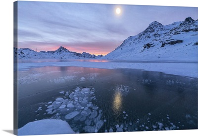 Ice bubbles frame the frozen Lago Bianco at dawn, Engadine, Switzerland