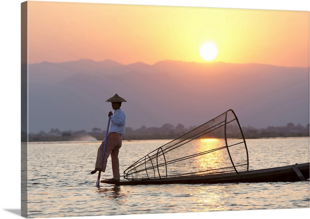 Intha leg rowing fishermen at sunset on Inle Lake who row traditional wooden boats using their leg and fish using nets str...