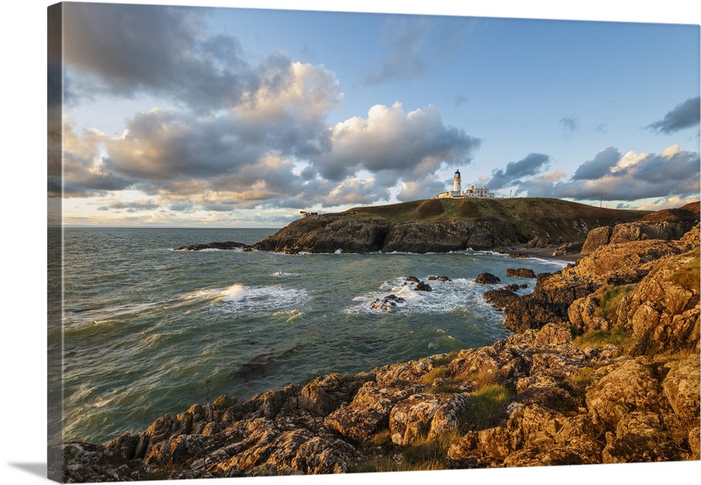 Killantringan Lighthouse on Black Head and rocky coastline at sunset, Portpatrick, Dumfries and Galloway, Scotland, United...
