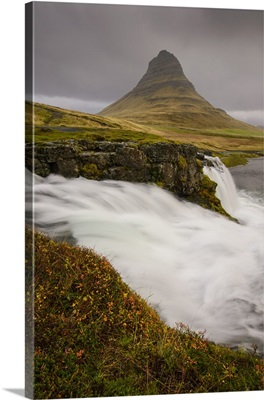 Kirkjufellsfoss in autumn with hiker to show scale, Iceland
