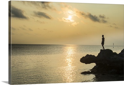 Man on a rock in backlight on the rocky west coast in Ouvea, New Caledonia
