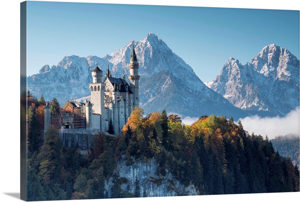 Neuschwanstein Castle surrounded by colorful woods and snowy peaks, Fussen, Bavaria, Germany