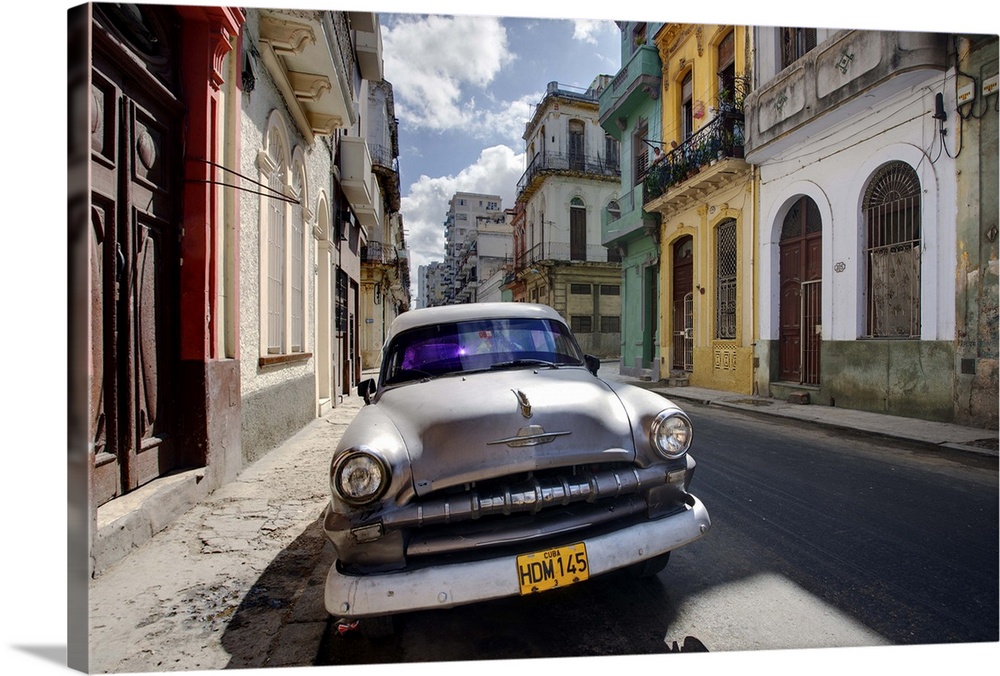 Old American Plymouth car parked on deserted street of old buildings, Havana, Cuba