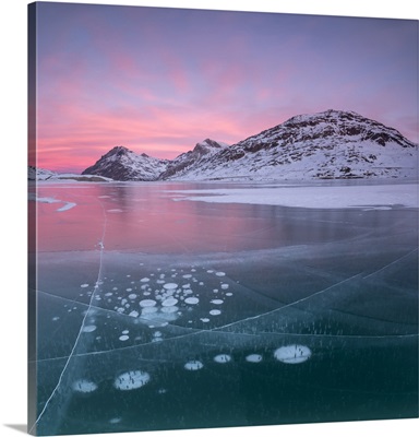 Panorama of ice bubbles and frozen surface of Lago Bianco at dawn, Engadine, Switzerland