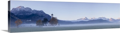 Panorama of St. Coloman Church surrounded by the autumn fog at sunrise