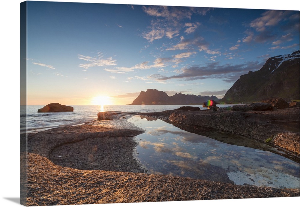 Pink clouds and midnight sun are reflected in the blue sea framed by rocky peaks, Uttakleiv, Lofoten Islands, Norway, Scan...