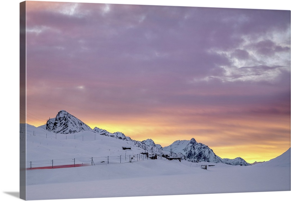 Pink clouds and snow frame the Bernina Express train at dawn, Bernina Pass, Canton of Graubunden, Engadine, Switzerland, E...