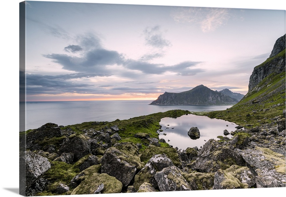 Pink clouds of the midnight sun reflected in the cold sea, Flakstad, Moskenesoya, Nordland county, Lofoten Islands, Norway...