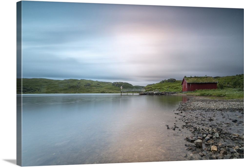 Pink lights of the midnight sun illuminate sea and the typical rorbu, Holdalsvatnet, Vestvagoy, Lofoten Islands, Norway, S...