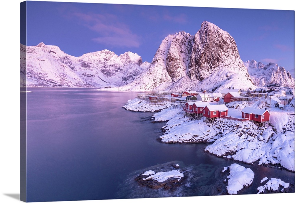 Pink sunrise on snowy peaks surrounded by the frozen sea around the village of Hamnoy, Nordland, Lofoten Islands, Arctic, ...