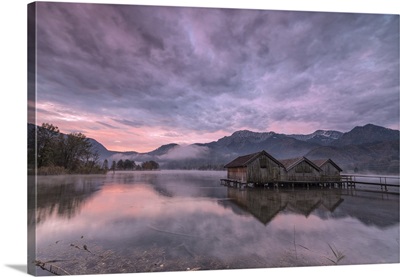 Purple sky and wooden huts are reflected in the clear water of Kochelsee, Germany