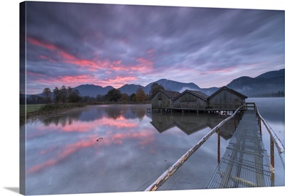 Purple sky and wooden huts are reflected in the clear water of Kochelsee, Germany