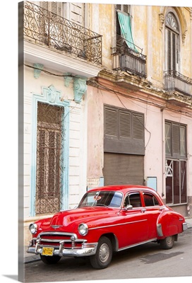 Red American car parked outside faded Colonial buildings, Havana, Cuba