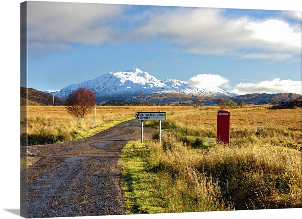 Winter view of a red telephone box and road toward snow covered Beinn Resipol mountain in the moors of the Scottish Highla...