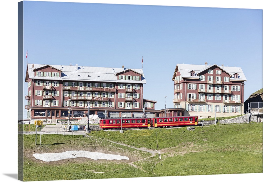 Red wagons of Wengernalpbahn rack railway run next to alpine hotels, Wengen, Bernese Oberland, Canton of Bern, Switzerland...